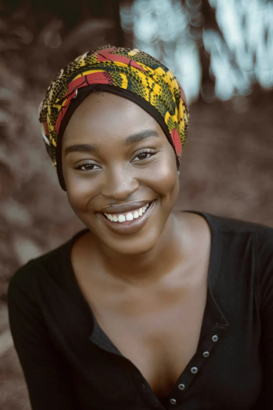 A smiling Nigerian woman wearing a colourful head wrap